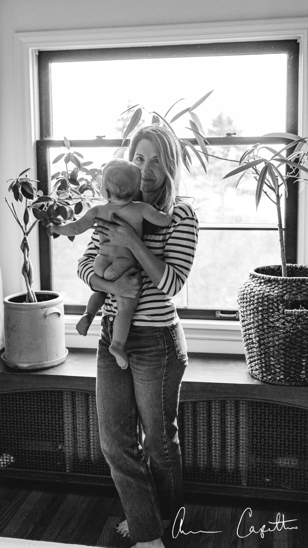 Black and white photo of a Anna Capretto, Village Maternity's CEO,  holding her baby.