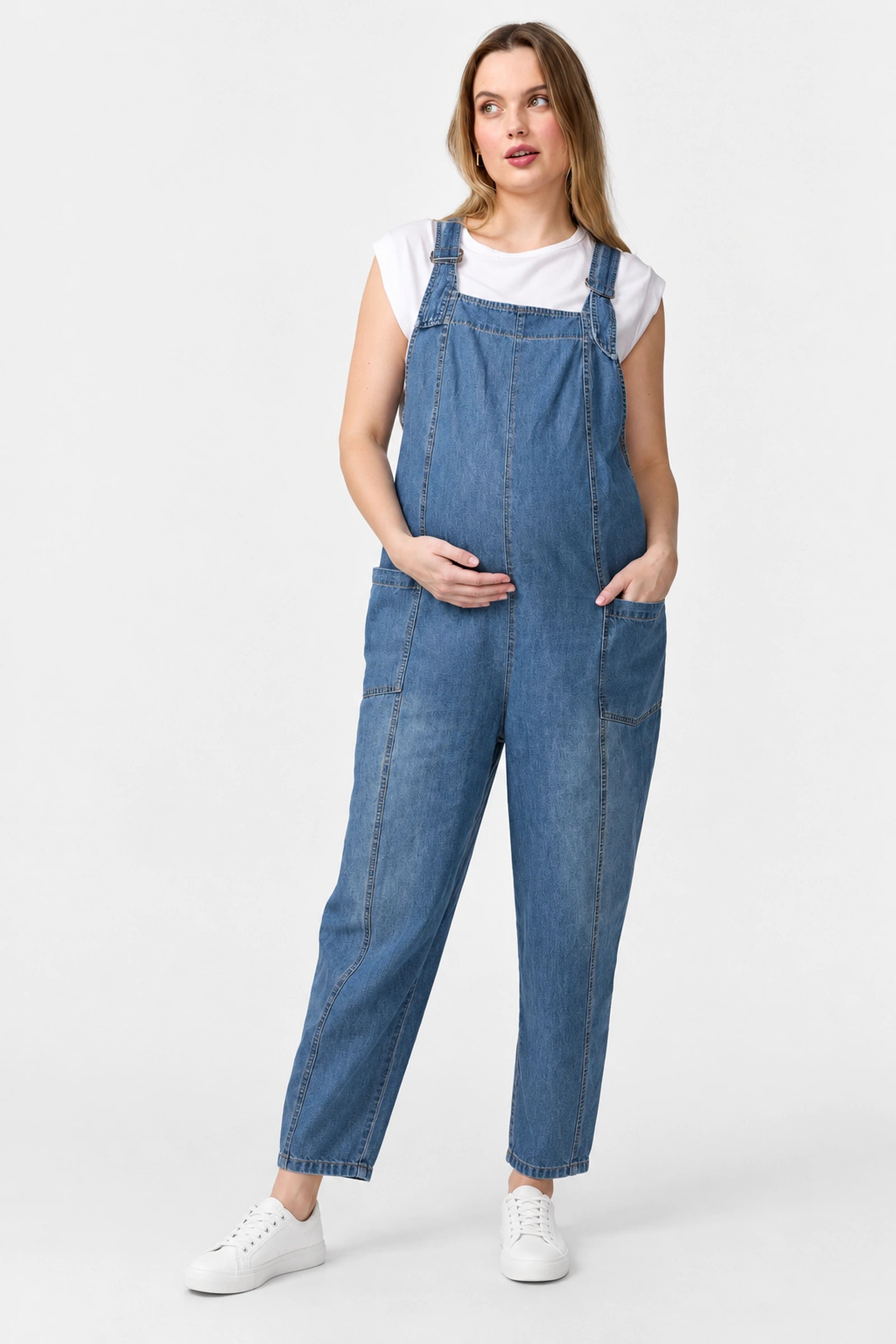 Front view of Ingrid & Isabel Everyday Denim Maternity Overalls in medium wash on a pregnant model.