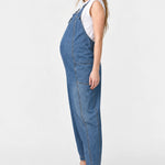 Side view of Ingrid & Isabel Everyday Denim Maternity Overalls in medium wash on a pregnant model.