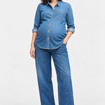 Front view of Ingrid & Isabel Relaxed Denim Maternity + Nursing Shirt in medium wash on a pregnant model.