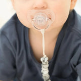 Baby with pacifier attached to onesie via marbled gray pacifier clip