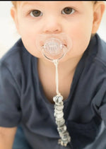 Baby with pacifier attached to onesie via marbled gray pacifier clip