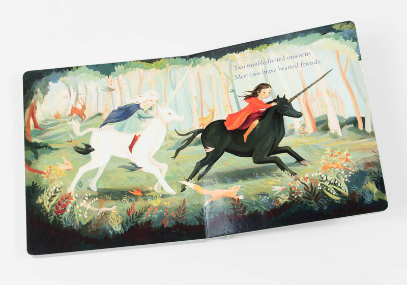 Interior image from book "Day Dreamers" by Emily Winfield Martin featuring 2 children riding unicorns through a forest with the text, "Two nimble footed unicorns meet two brave hearted friends."