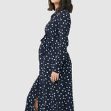 Spot shirt dress in navy with white polka dots. For maternity and nursing with button access for nursing and tie empire waist. Long sleeves and calf-length dress cut. 