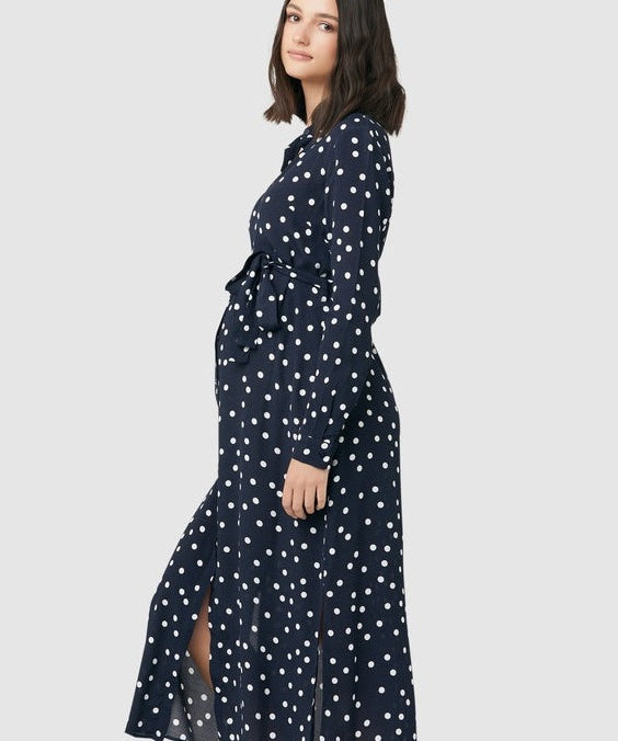 Spot shirt dress in navy with white polka dots. For maternity and nursing with button access for nursing and tie empire waist. Long sleeves and calf-length dress cut. 