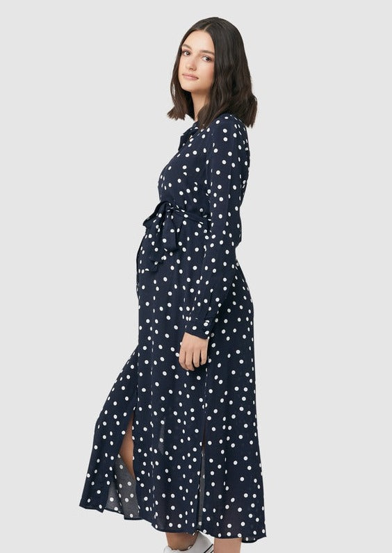 Spot shirt dress in navy with white polka dots. For maternity and nursing with button access for nursing and tie empire waist. Long sleeves and calf-length dress cut. 