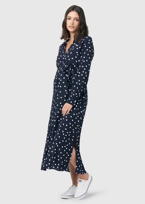 Spot shirt dress in navy with white polka dots. For maternity and nursing with button access for nursing and tie empire waist. Long sleeves and calf-length dress cut. 