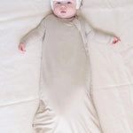 Baby wearing Kyte Baby Sleep sack in 1.0 TOG weight in light brown oat color