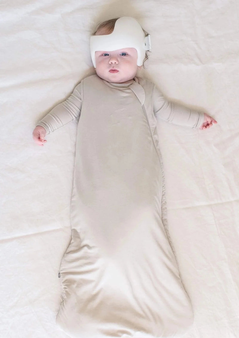 Baby wearing Kyte Baby Sleep sack in 1.0 TOG weight in light brown oat color
